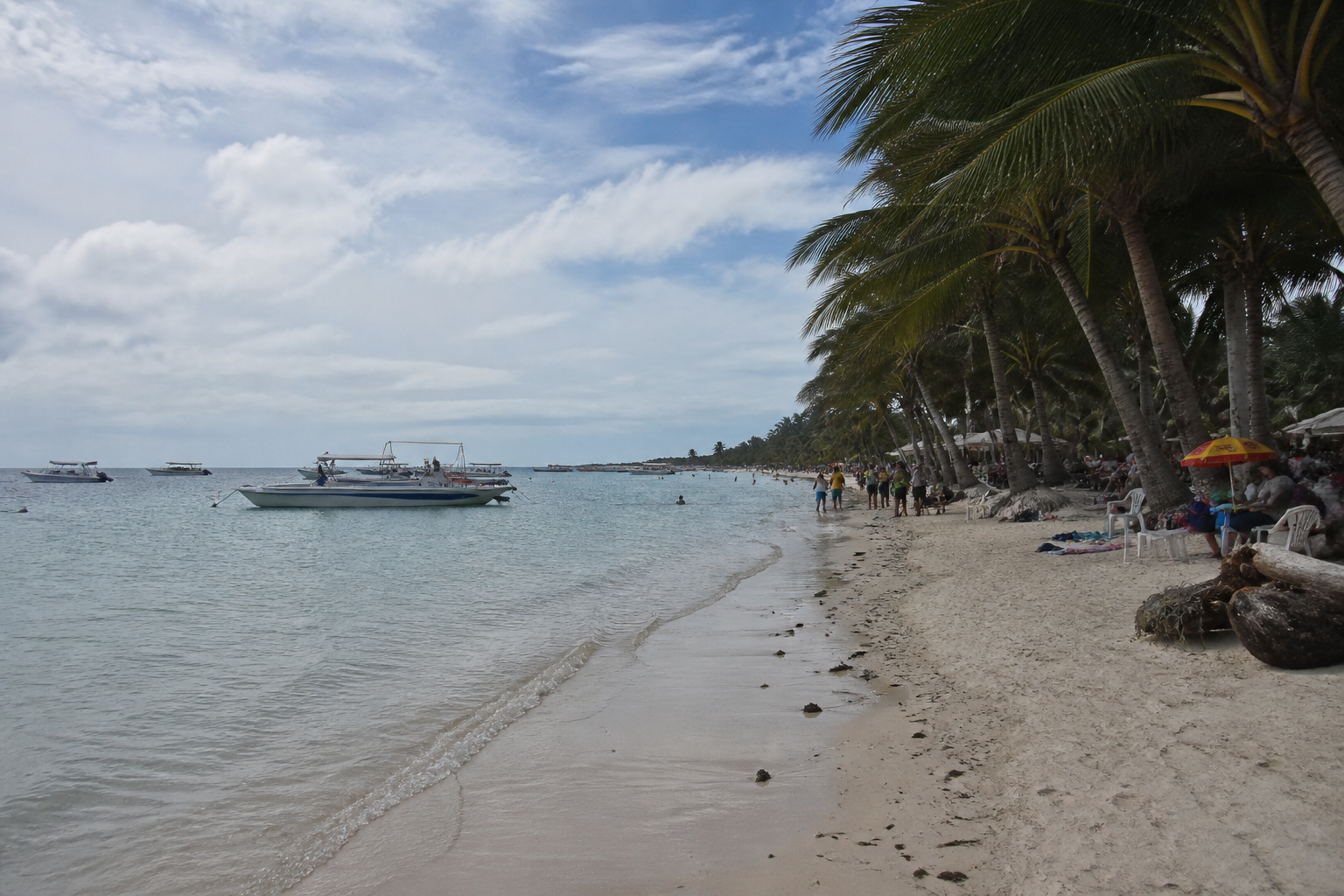 A tropical shoreline with boats and beach activity