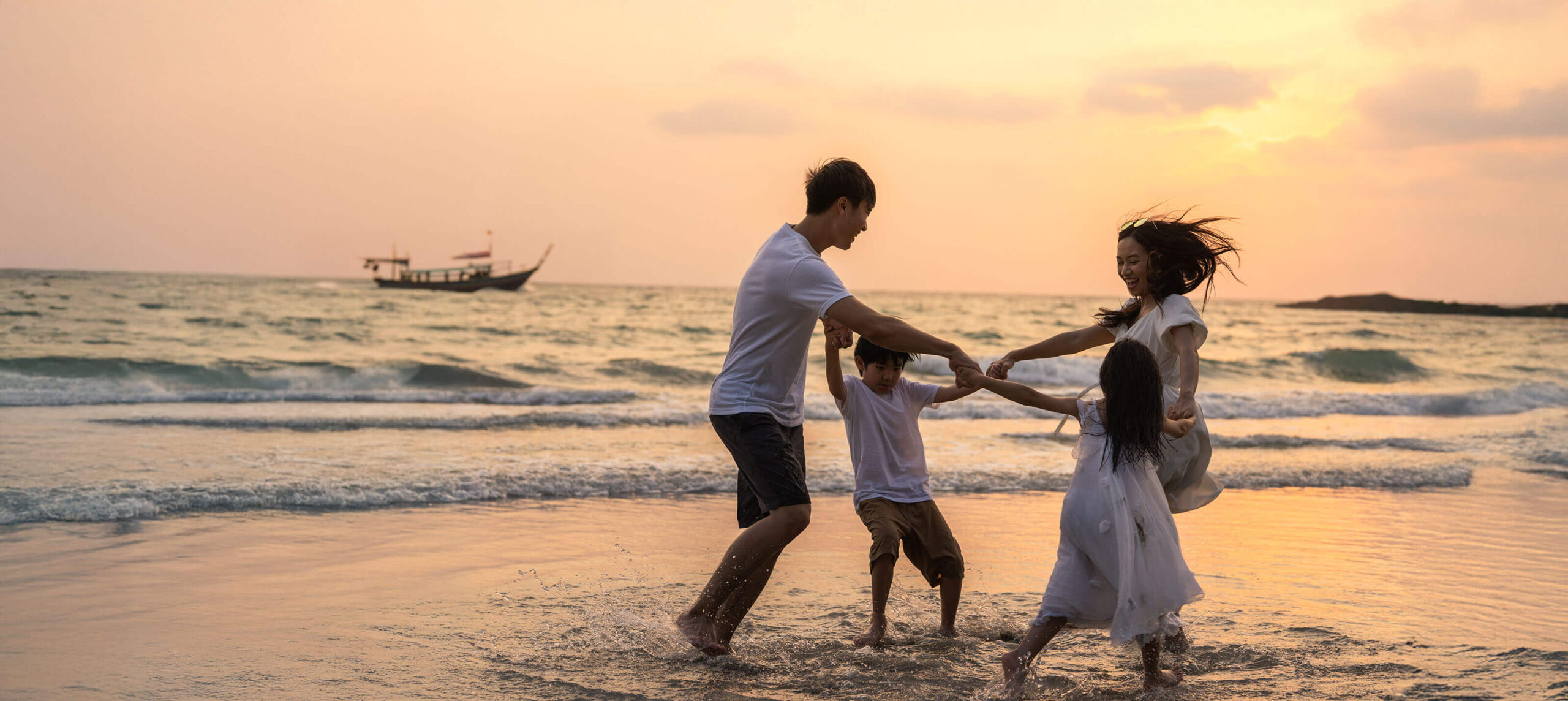 A family playing together at the shoreline during sunset