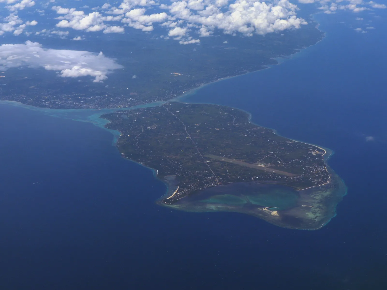 Panglao Island seen from an aircraft, a flat green island ringed by pale shallows, with the larger Bohol mainland beyond