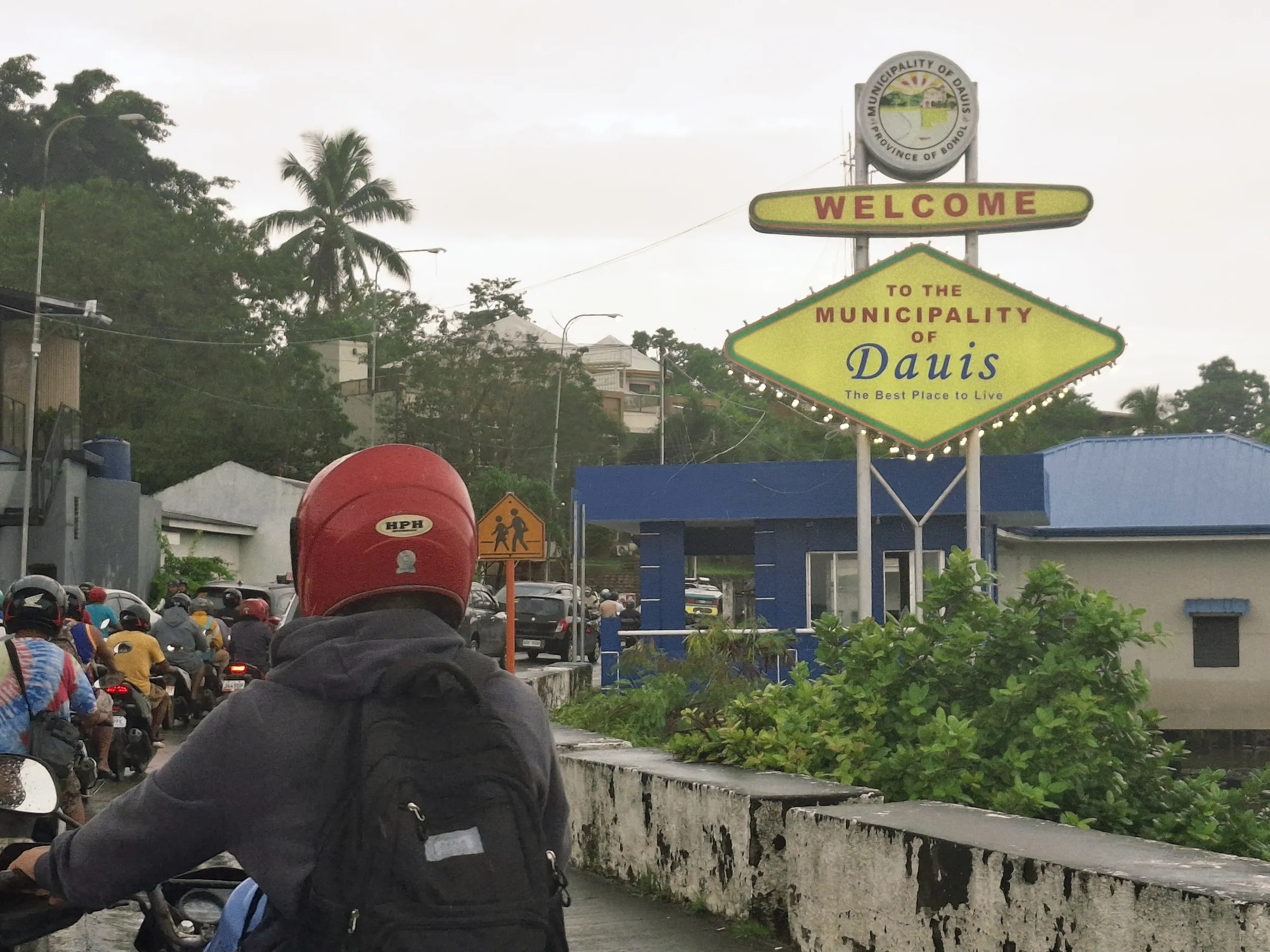 Motorbike riders passing the Welcome to Dauis sign on the road onto Panglao Island